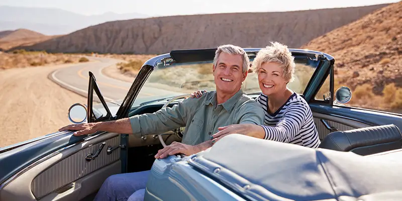 An elderly couple in a classic convertable car